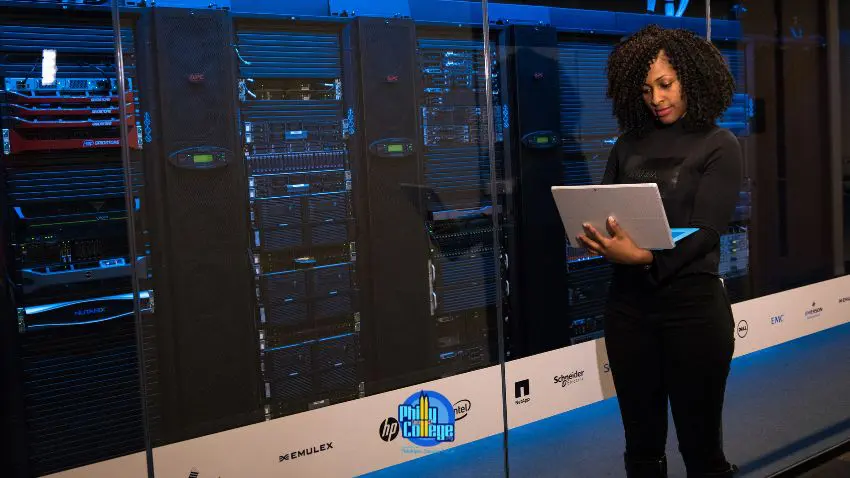 a person standing in front of a server room with a laptop