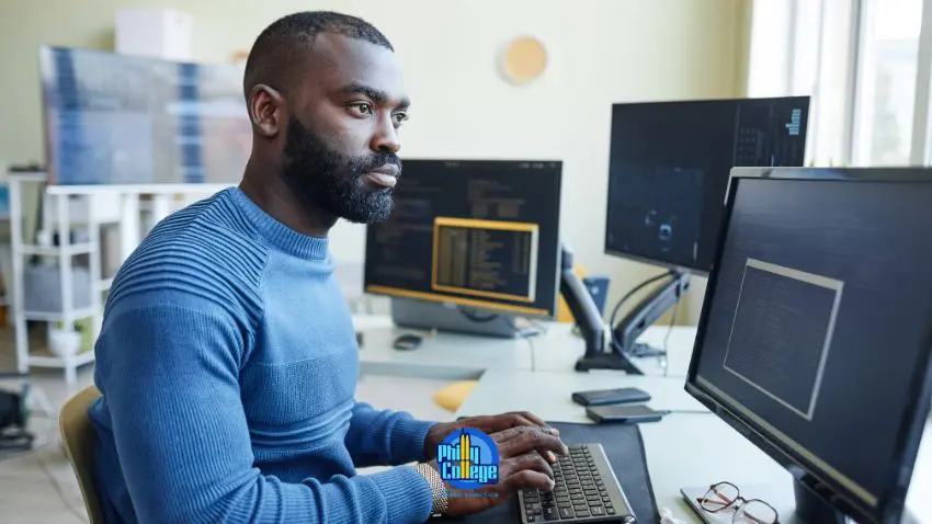 A man sitting at a desk in front of two computer monitors