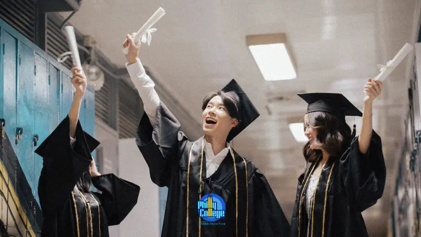 three students in graduation gowns holding up their diplomas