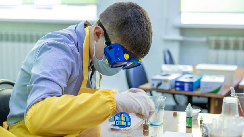 A person in a lab coat and goggles is working on something