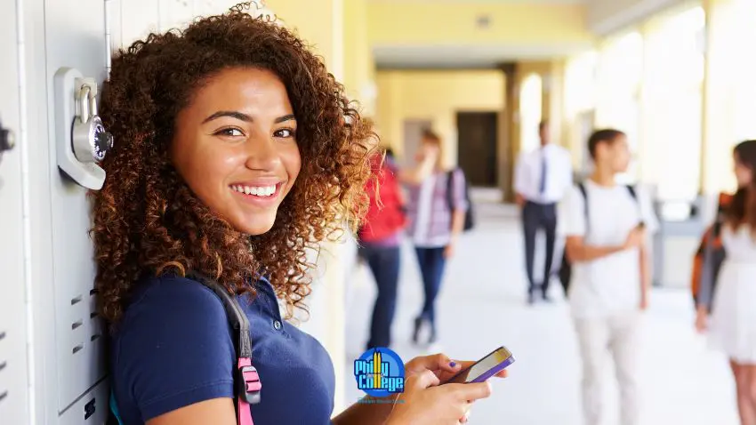 portrait of a girl using her cell phone in the hallway of a high school
