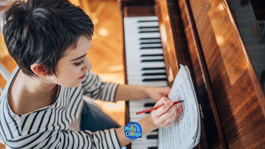 A person is writing on a piece of paper while sitting at a piano.