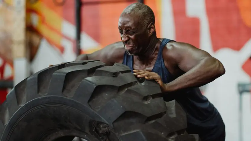 a person is lifting a large tire in a gym