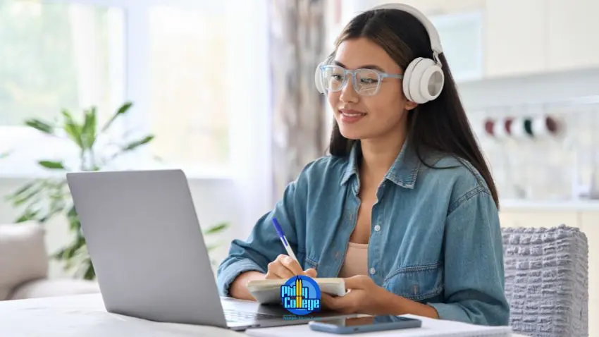 A person with headphones and glasses is working on their laptop