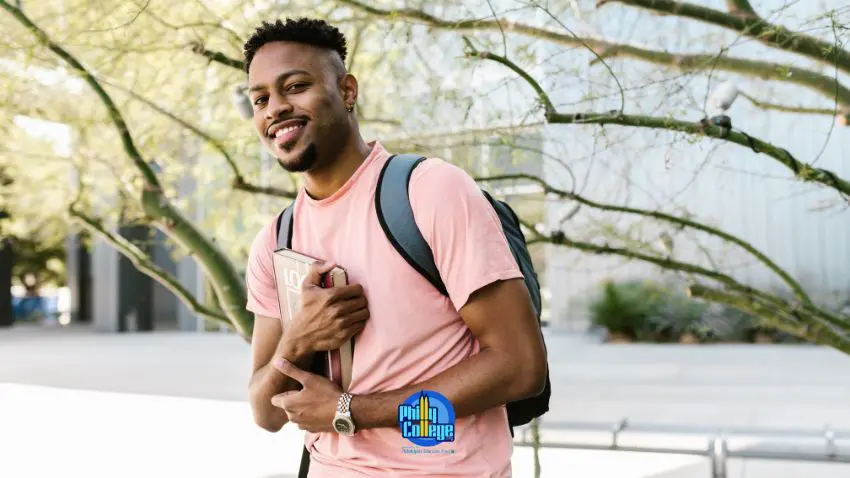 a smiling person with a backpack standing in front of a tree