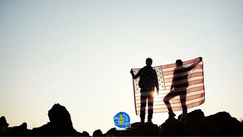 two people standing on top of rocks holding an american flag