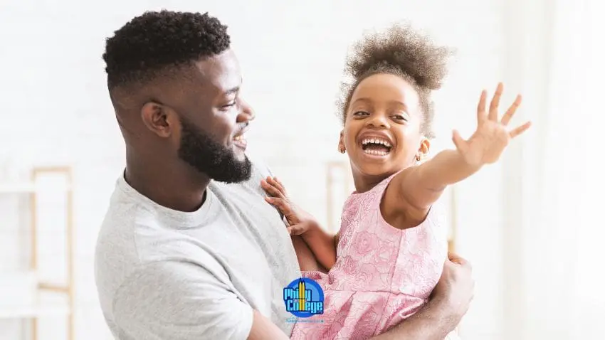 A man holding a child who is laughing and waving her hand.