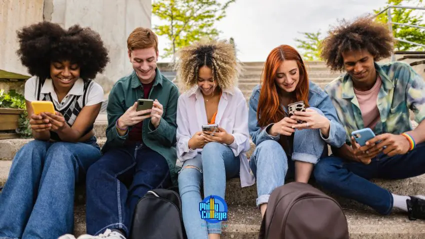 A group of people sit on outdoor steps looking at their phones.