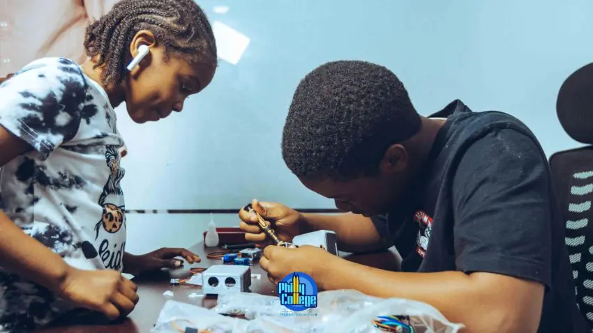 two people working on electronics at a desk