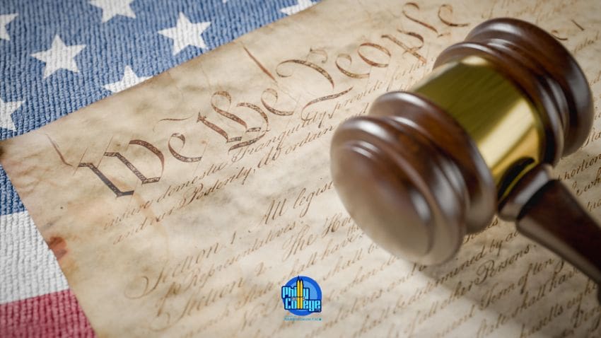 A gavel rests on the U.S. Constitution with the American flag in the background.