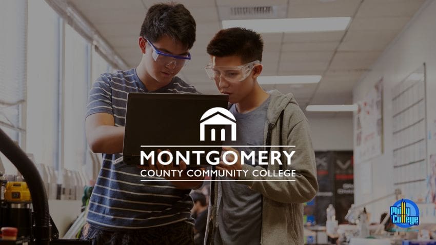 two students looking at laptop standing up in the middle of a lab