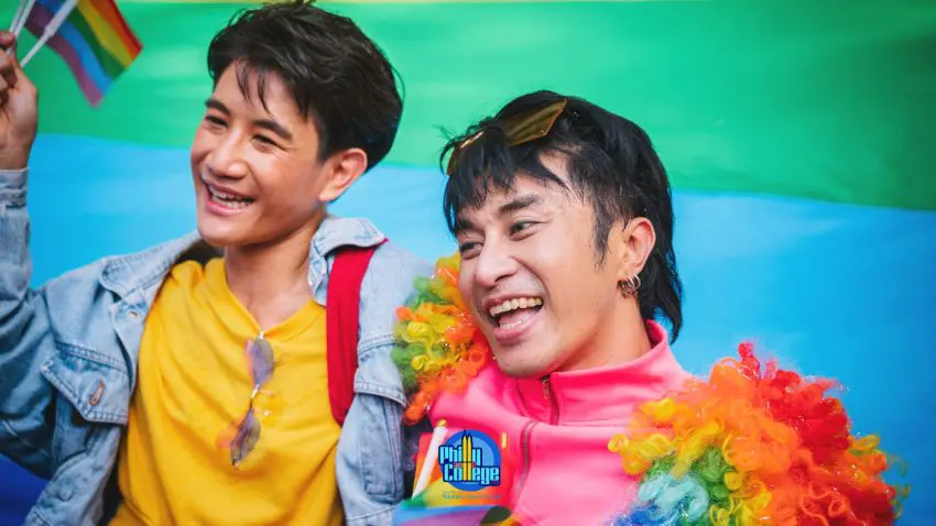 Two men are smiling and holding rainbow flags